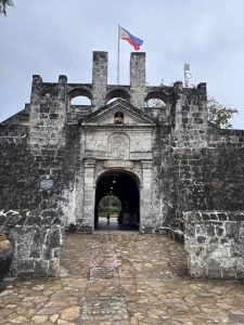 Historic entrance of Fort San Pedro in Cebu with stone walls and the Philippine flag above. 