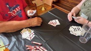 Seen from above, the hands of two people playing a game of cards on a table.