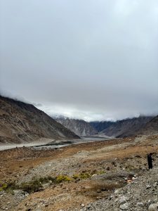 Remote mountain valley with rocky slopes and clouds obscuring the surrounding peaks. 