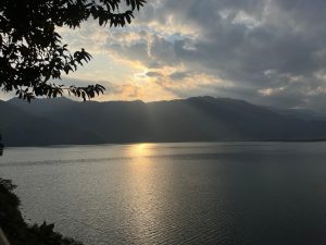 Sunset over a tranquil lake with rippling water reflecting the golden light. 