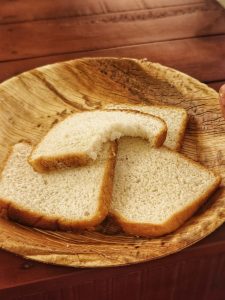 Two slices of soft white bread with a bite taken out, resting on a rustic wooden plate 