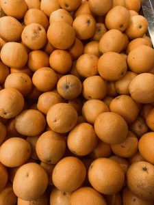 A close-up view of a large pile of bright orange tangerines, highlighting their smooth, slightly dimpled texture and vibrant.