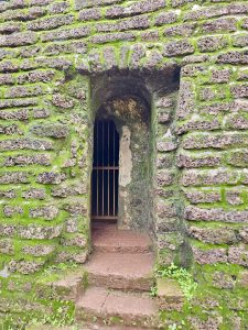 A narrow arched entrance leads into an old chamber within the fort. Moss-covered laterite stones and weathered walls create a mysterious atmosphere, revealing a glimpse of the fort’s past. Captured at St. Angelo Fort, Kannur, Kerala.

