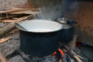Rustic firewood stove with milk boiling in a blackened pot, a timeless glimpse into rural life and tradition. 
