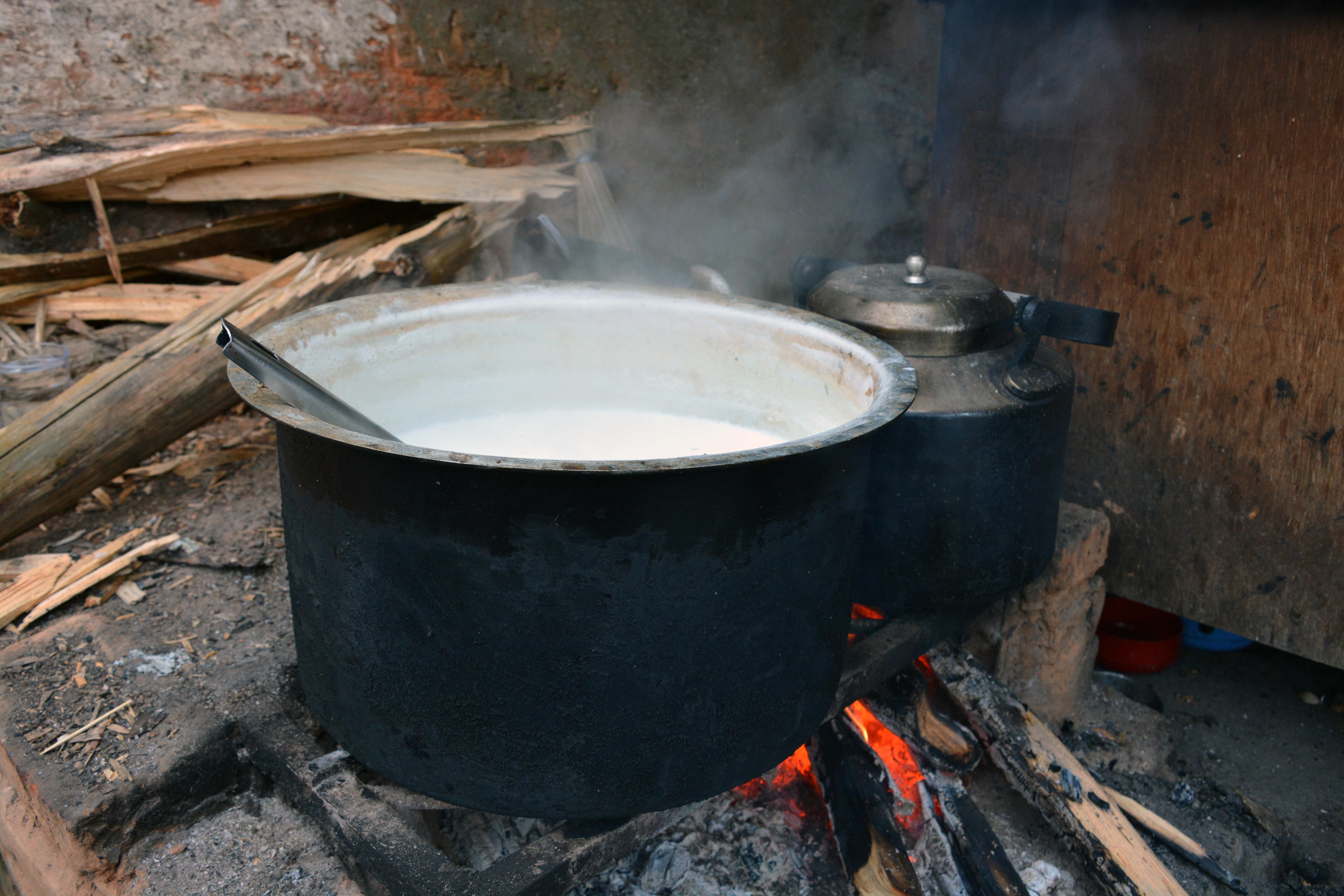 Rustic firewood stove with milk boiling in a blackened pot, a timeless glimpse into rural life and tradition.