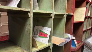 An old fashioned mail sorter, open slots in a wooden shelving system.
