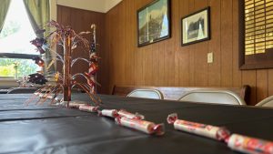 Candies arranged in the middle of a table, making a strip down the middle, seen close up.  In the middle of the table is a vertical spray of decorative plastic, meant to look like fireworks.

