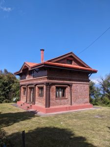 Traditional Newari-style red brick building with carved wooden columns and red tiled roof on a hilltop 