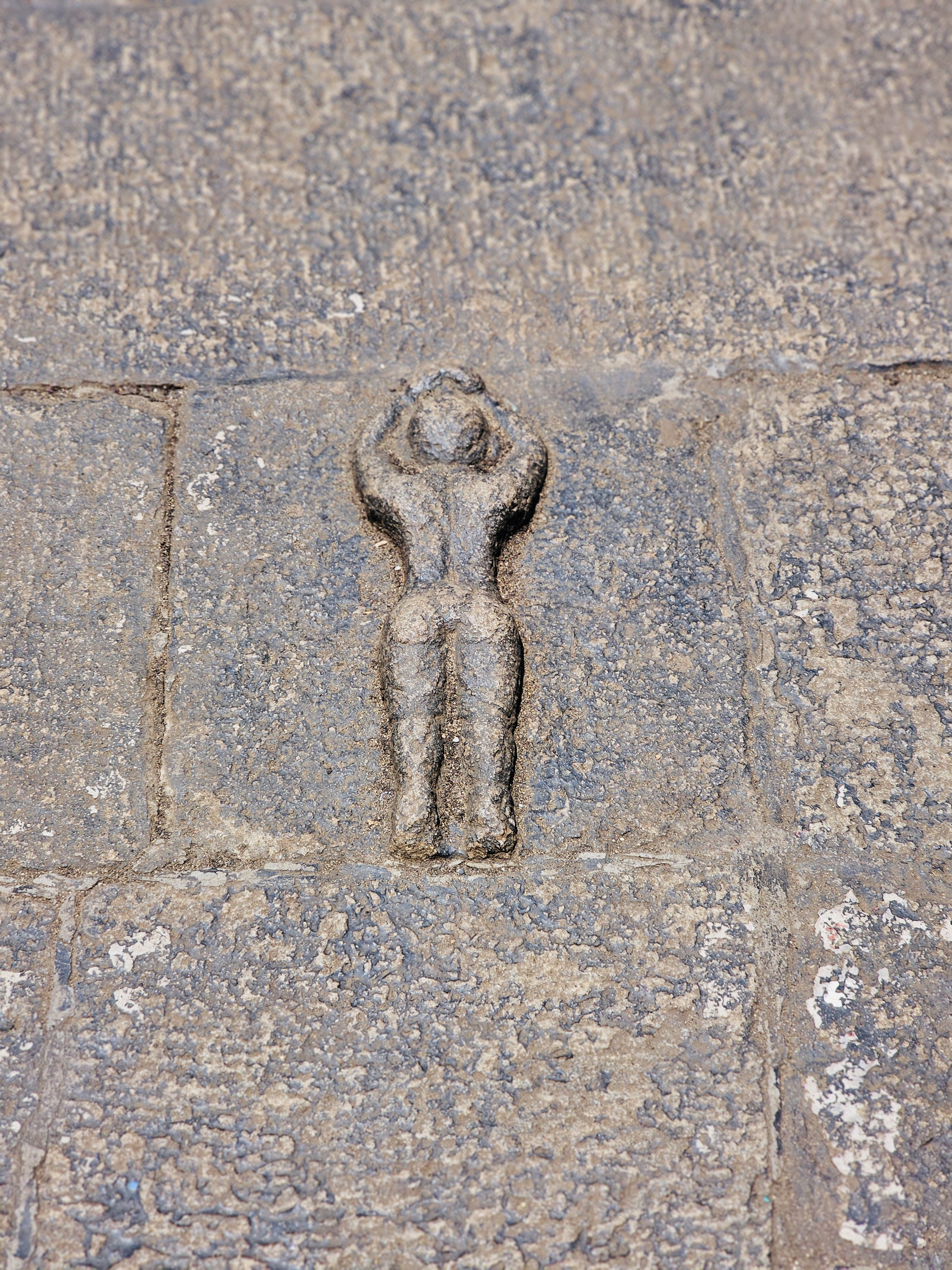A small carved human figure in a yoga pose is embedded in the old stone floor, reflecting the subtle artistry of Kerala's historic architecture. Such carvings were traditionally associated with ritual practices at the heritage mansion. Captured at Varikkasseri Mana, Vaniyamkulam, Palakkad.