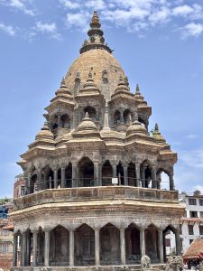 The Krishna Mandir, a rare shikhara-style stone temple with multiple tiers of arched colonnades and a large dome topped with a golden finial, Patan Durbar Square, Nepal. 