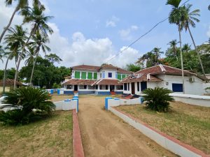 A beautiful traditional Kerala-style heritage house surrounded by coconut palms and greenery. The tiled roofs, spacious courtyard, and classic architecture reflect the cultural charm of rural Kerala. Captured at Kollengode, Palakkad District, Kerala. 