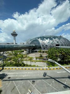 Jewel Changi Airport exterior with curved glass architecture and nearby control tower. 
