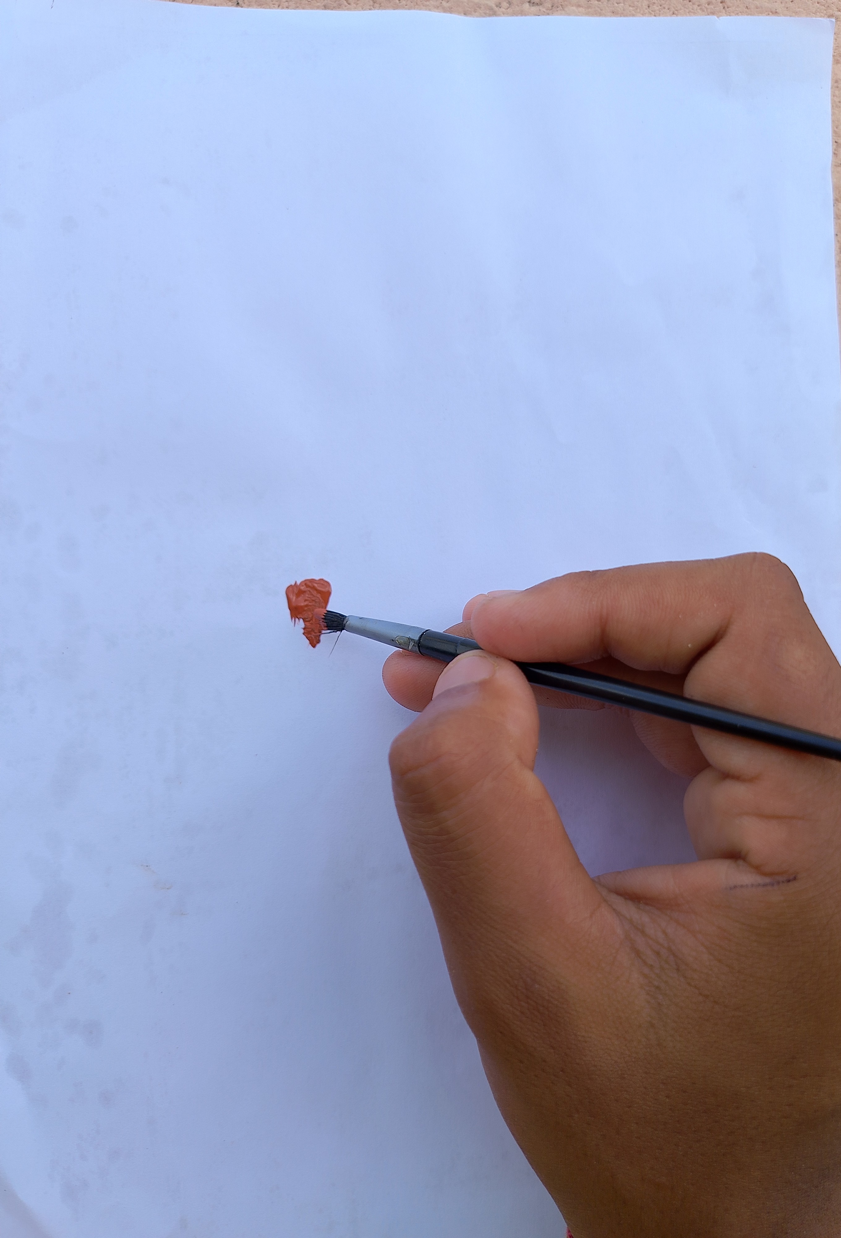 Hand painting with a fine brush and red paint on white paper.