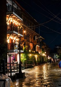 Warmly lit heritage brick building with ornate wooden balconies and wrought iron street lamps glowing against a deep night sky 