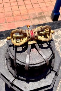 Gilded vajra atop a carved stone dharmachakra with a marigold offering, Kathmandu. 