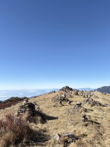 Stone cairns lining a sunlit mountain ridge above the clouds. 