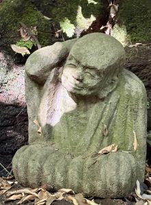 A stone statue seemingly listening to the sounds of nature, hidden deep within the forest.