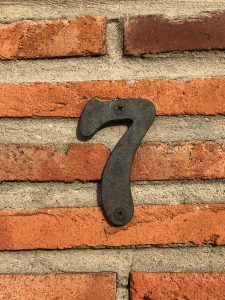 A number seven made of metal on a brick and concrete wall