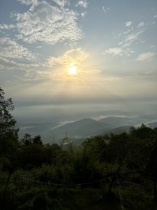 A scenic landscape with the sun rays over the horizon covered with dappled clouds 