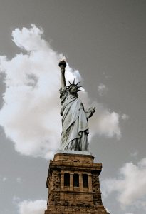 Statue of Liberty towering over dramatic cloudy skies, torch raised high 