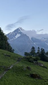 A serene mountain landscape at dawn with a snow-capped peak under a clear blue sky. 
