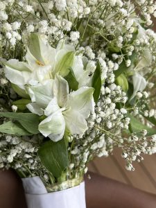 Close-up of white lilies and baby’s breath in a floral arrangement.