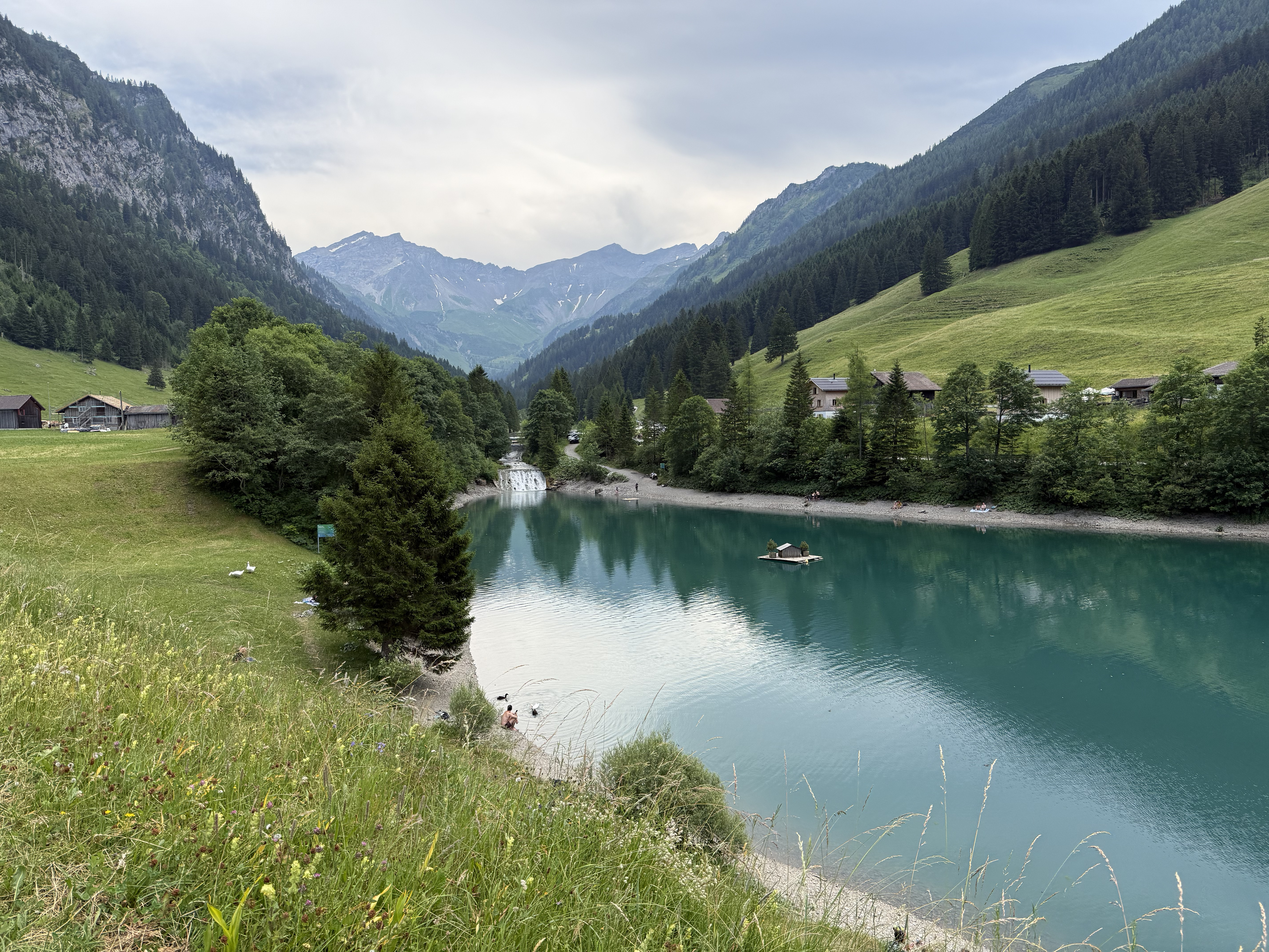 View of Gänglesee in Malbun, Liechtenstein, surrounded by alpine mountains, forested slopes, and clear natural scenery.