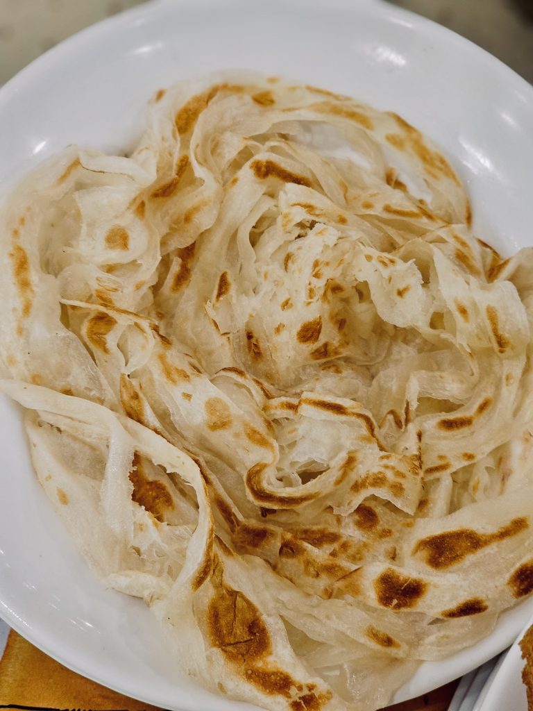 Soft, flaky Kerala porottas with golden, toasted layers, freshly prepared and ready to enjoy with curry. A popular South Indian favorite. Captured in Palazhi, Kozhikode, Kerala.