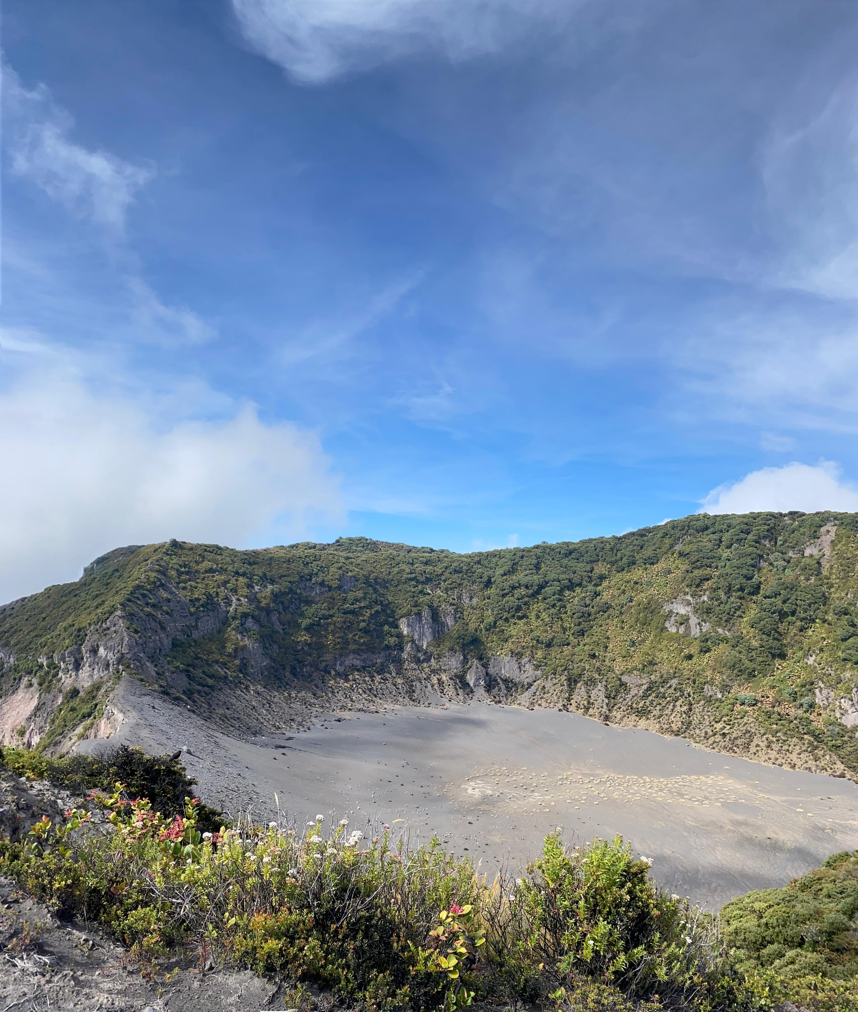 A volcanic crater surrounded by green cliffs and rugged rocky terrain.