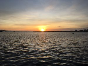 Sunset over the water in Cambados, Spain, with the sun reflecting on the calm sea.