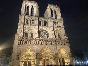 Front facade of Notre-Dame Cathedral illuminated at night in Paris, France.