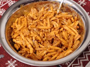 A bowl of crispy fries is coated in a rich, creamy, spicy sauce, making it a delicious and tempting snack. The vibrant colors and generous coating make the dish look extra flavorful.