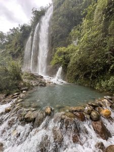 A breathtaking natural waterfall in Pokhara, Nepal, flowing gracefully through lush green hills during the monsoon season.
