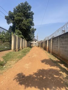 A narrow ruaral road in Kampala city leads through stone walls
