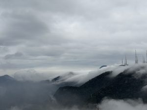 Mountain peaks covered in mist with communication towers rising above the clouds.