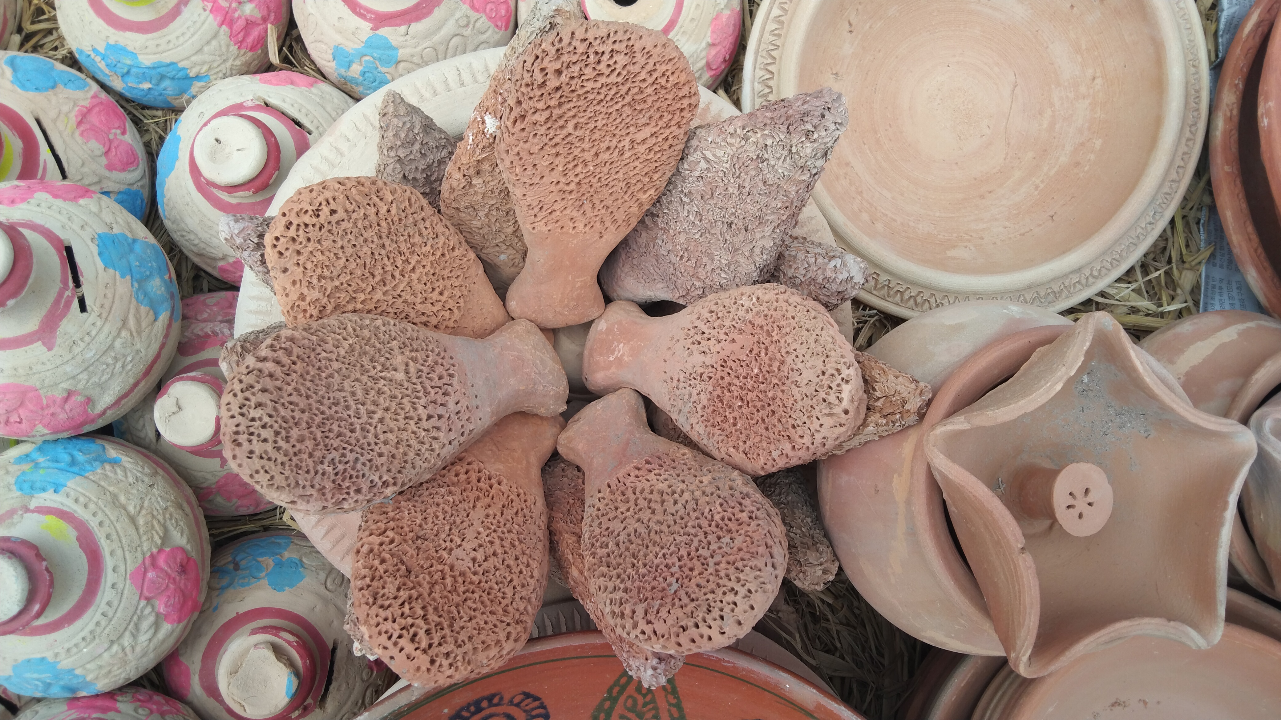 Terracotta pottery with clay ornaments, painted pots, and handmade designs on display.