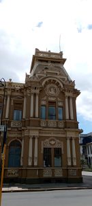 Corner view of the Correos y Telégrafos building in San José, Costa Rica, featuring a decorative tower with Corinthian columns, a carved medallion portrait and neoclassical ornamentation.