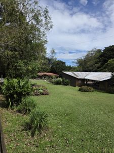 Large green area with flower gardens and rural cabins in the background.
