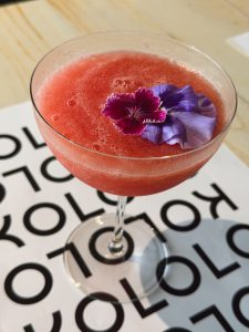 
A watermelon drink garnished with a purple flower.