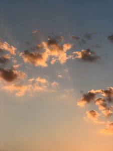 Golden sunset clouds glowing in the evening sky with warm orange and blue tones
