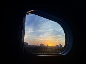 Round window framing a colorful sunset over a city skyline.