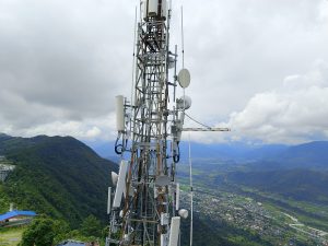 Telecommunications tower with multiple antennas and satellite dishes overlooking Pokhara valley and city from a hilltop viewpoint, Nepal