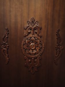 An elegant hand-carved wooden panel showcases detailed floral and geometric patterns, highlighting the beauty of traditional craftsmanship. The rich wood tones and symmetry make it a timeless decorative piece. Captured in Kaloor, Ernakulam.

