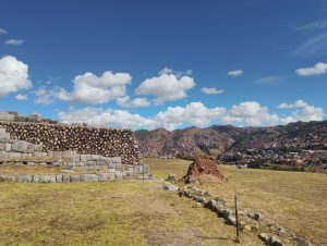 View of the outskirts of Cusco from Sacsayhuaman, Peru. A section of an Inca stone wall is visible in the foreground, while the city spreads across the landscape in the distance.
