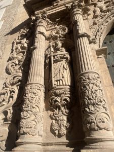 Baroque stone sculpture framed by ornate carved columns on the facade of Murcia Cathedral in Murcia, Spain.
