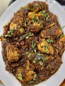 A spicy Kerala-style chicken roast cooked with onions, curry leaves, and aromatic spices. The thick masala and fresh coriander make it look flavorful and inviting. Captured in Palazhi, Kozhikode, Kerala.