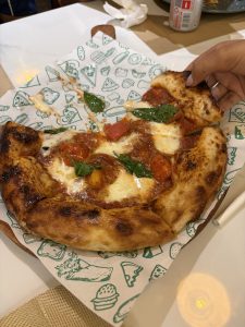 
A freshly baked pizza sits on a patterned paper, showcasing a golden-brown crust with crispy edges.