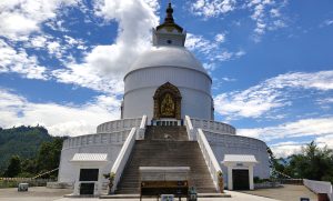 A white edifice crowned with a statue, highlighting its architectural significance in the surrounding landscape.