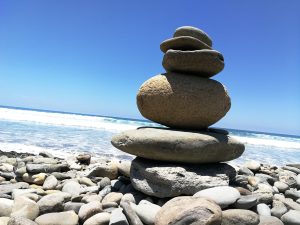 A stack of smooth stones balanced on a rocky beach.
