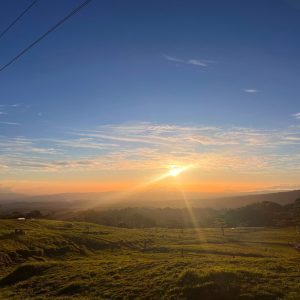 A breathtaking view of a sunset over rolling hills, with a vibrant orange and yellow light illuminating the sky. 
